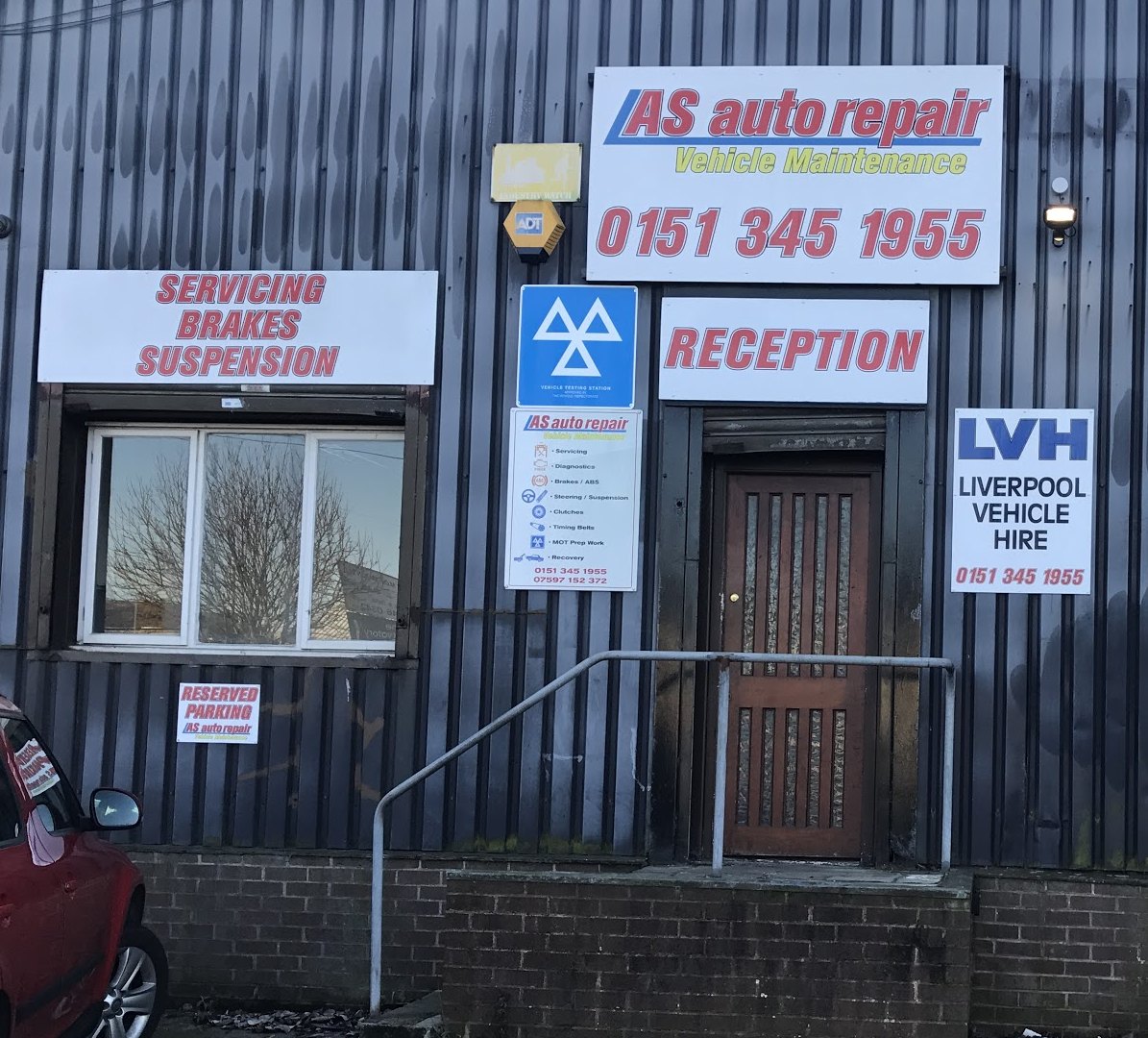 The front of the unit: the AS auto repair sign with the phone number, the servicing, brakes and suspension sign, the blue MOT sign and the reception door