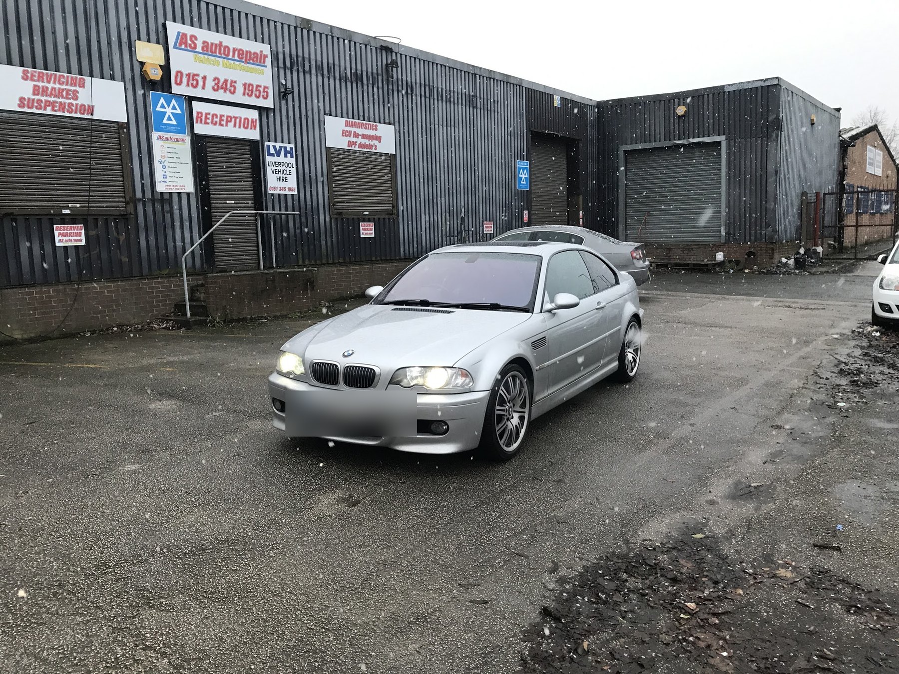 A silver BMW parked in the yard in front of the AS Auto Repair unit